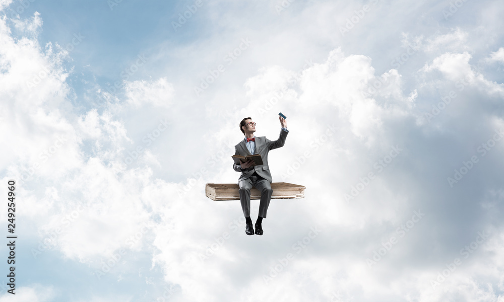 Young businessman or student floating in blue sky and studying the science Young businessman or student floating in blue sky and studying the science