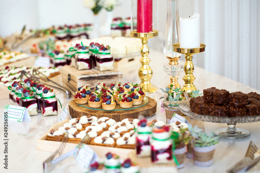 Delicious wedding reception candy bar dessert table full with cakes and sweets and a candles