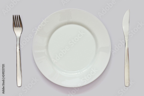 empty white plate, knife and fork on white table. Table setting