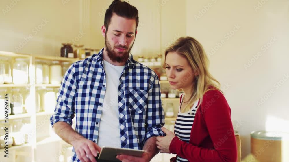 Young shop assistant with tablet serving an attractive woman in a zero waste shop. Young shop assistant with tablet serving an attractive woman in a zero waste shop.