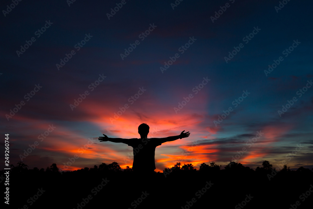 Silhouette of a male holding hands at sunrise.