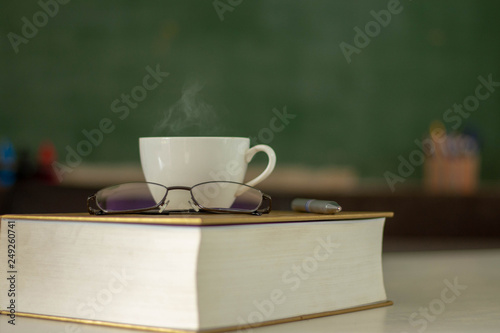 The white coffee cup is placed on the book on the desk at break time.
