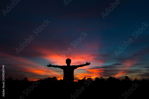 Silhouette of a male holding hands at sunrise.