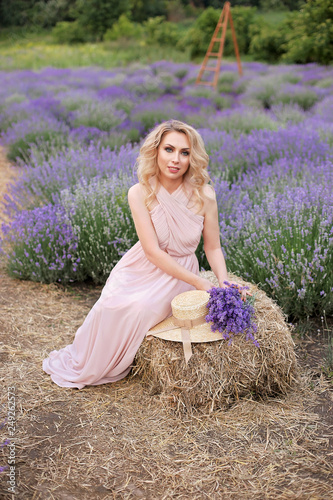 Pretty girl in a lavender field holding a bouquet of lavender.