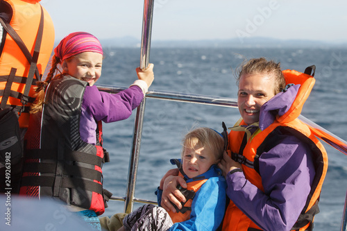Obraz na płótnie Family on a blue whale watching trip. Smiling girl in safety jacket on a boat trip. Mother holding baby.. w salonie