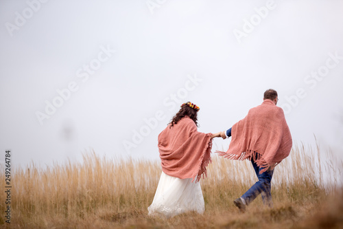 bride and groom wrapped in blanket in yellow field