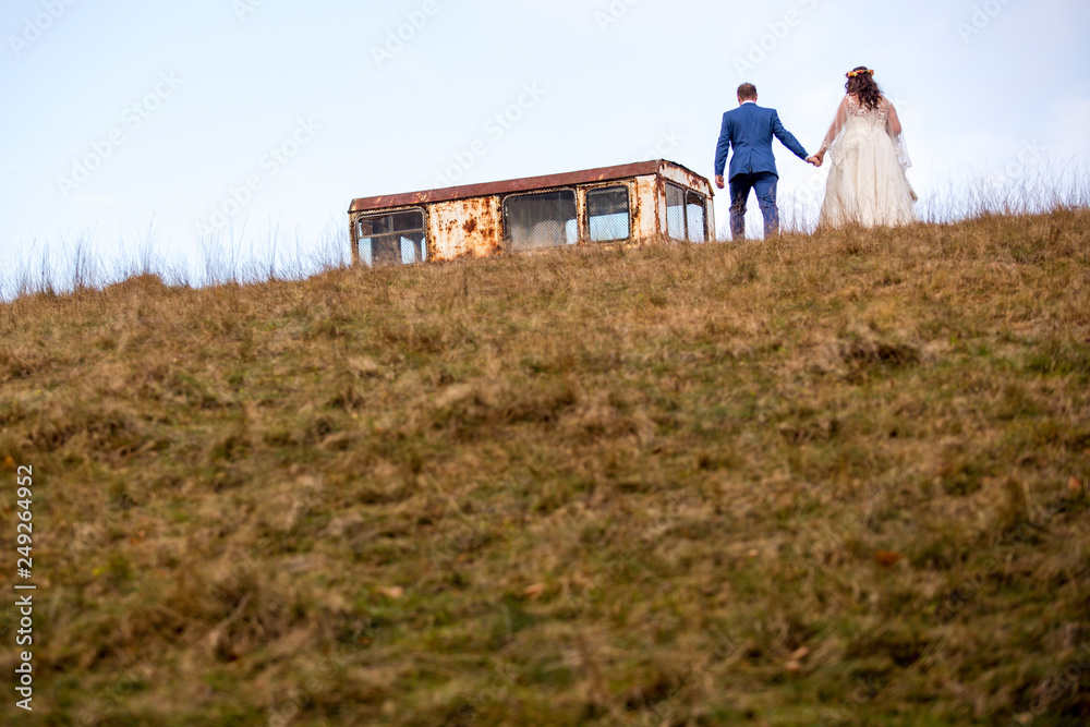 Obraz premium Beautiful wedding couple posing on hill at countryside