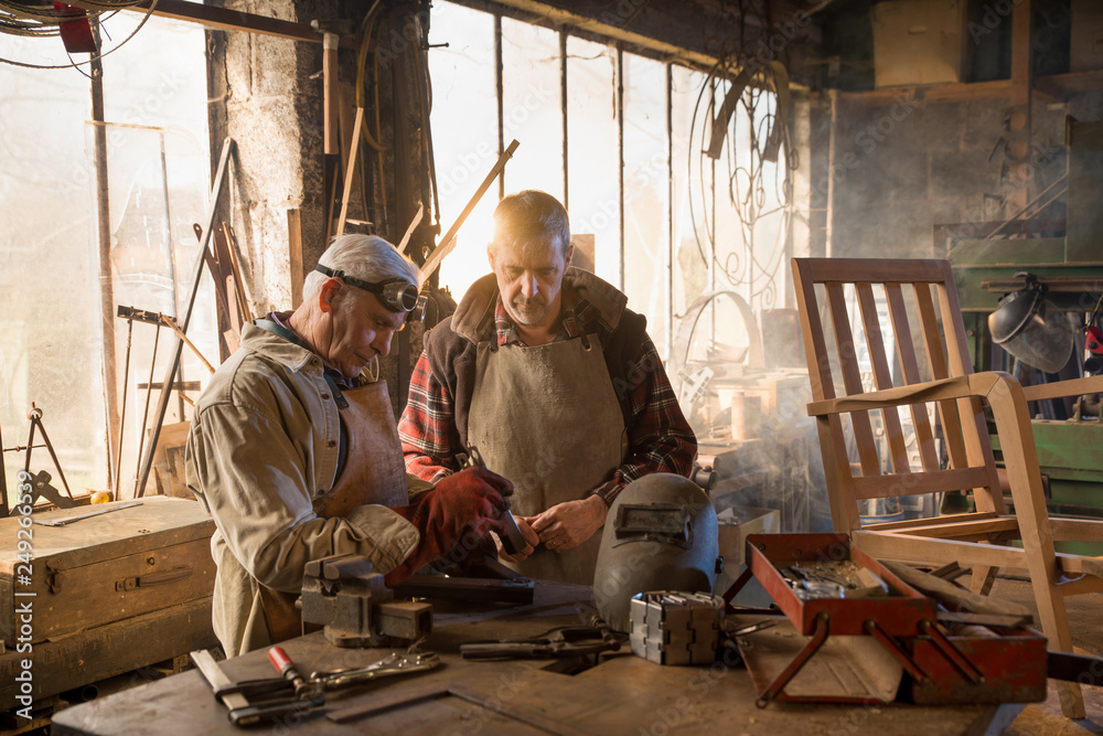 Two craftsmen in their craft workshops work metal parts Two craftsmen in their craft workshops work metal parts