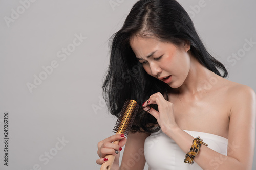 Portrait of asian woman long hair with a comb and problem hair on grey background. This image for hair loss concept. Free from copy space.