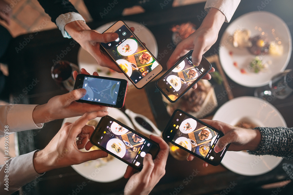 Group of friends going out and taking a photo of food together with mobile phone - obrazy, fototapety, plakaty 