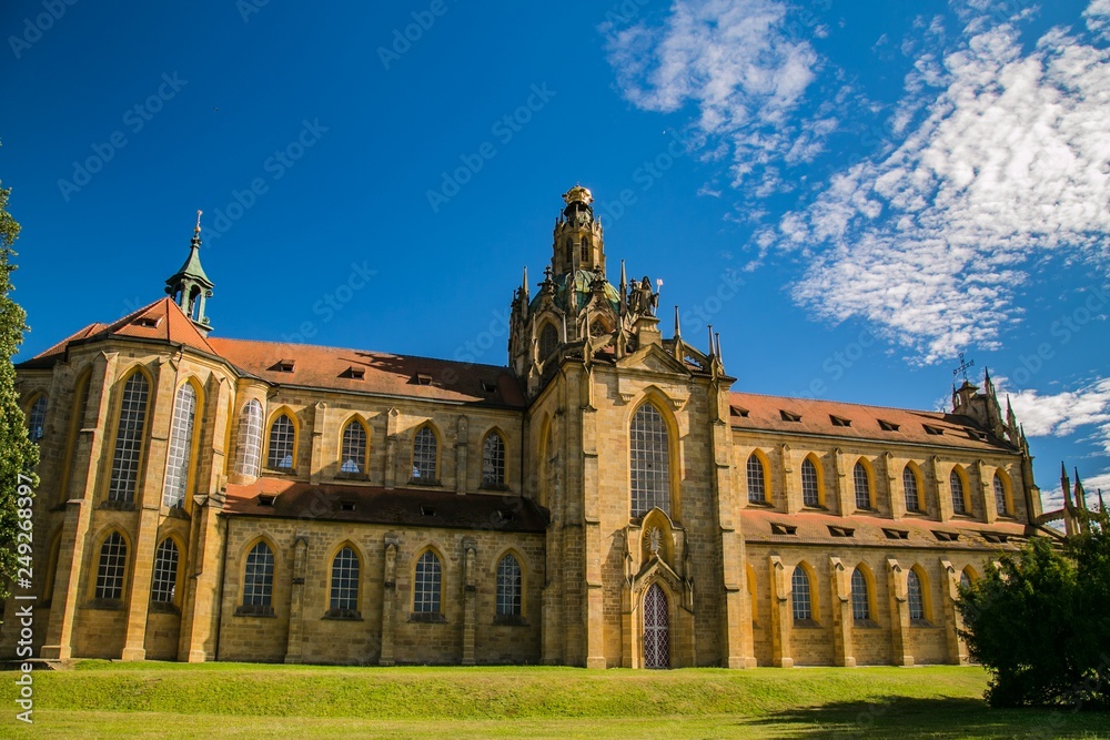 Kladruby, Czech Republic / Europe - July 7 2018: Church of the Assumption of the Virgin Mary built in baroque gothic style, yellow historical building, sunny day, green grass, blue sky with clouds