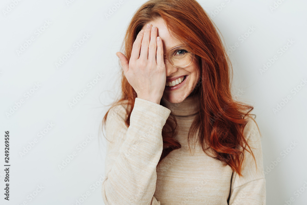 Smiling attractive woman covering one eye Smiling attractive woman covering one eye