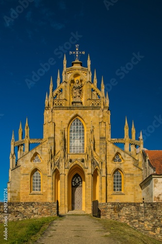 Kladruby, Czech Republic / Europe - July 7 2018: Church of the Assumption of the Virgin Mary built in baroque gothic style, yellow historical building, sunny summer day, blue sky, vertical image