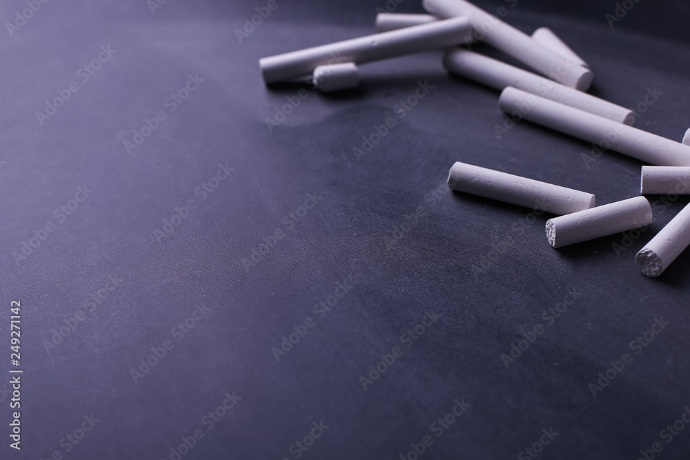 Naklejka premium Crayons lie on a black chalkboard, copy space. The concept of school, education and childhood.