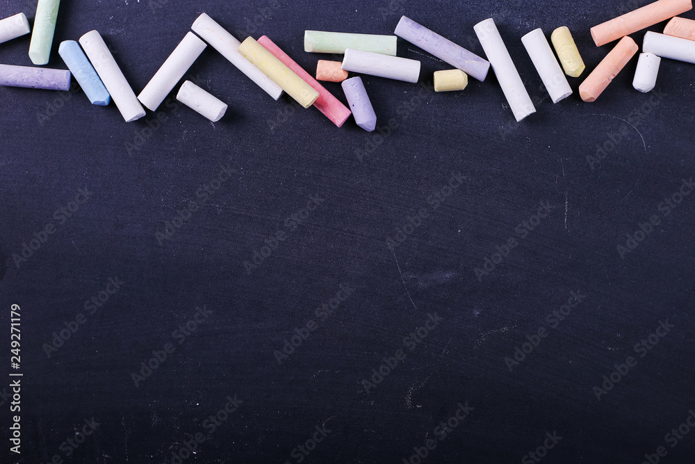 Multicolored crayons lie on a black chalkboard, copy space. The concept of school, education and childhood. Multicolored crayons lie on a black chalkboard, copy space. The concept of school, education and childhood.