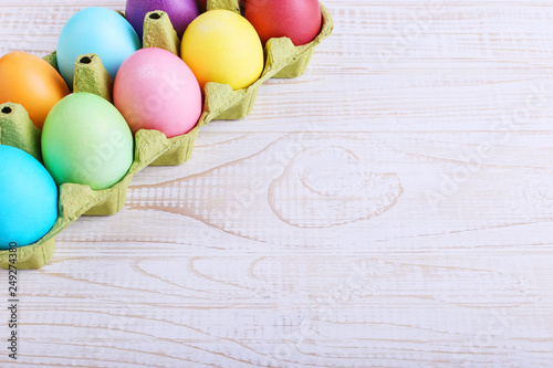 Colored Easter eggs in a pan, on a white wooden table.