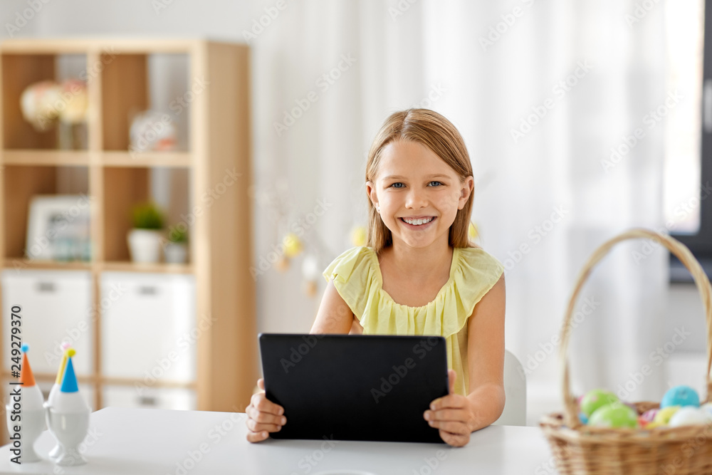 easter, holidays and people concept - happy girl with tablet pc computer and basket of colored eggs at home easter, holidays and people concept - happy girl with tablet pc computer and basket of colored eggs at home
