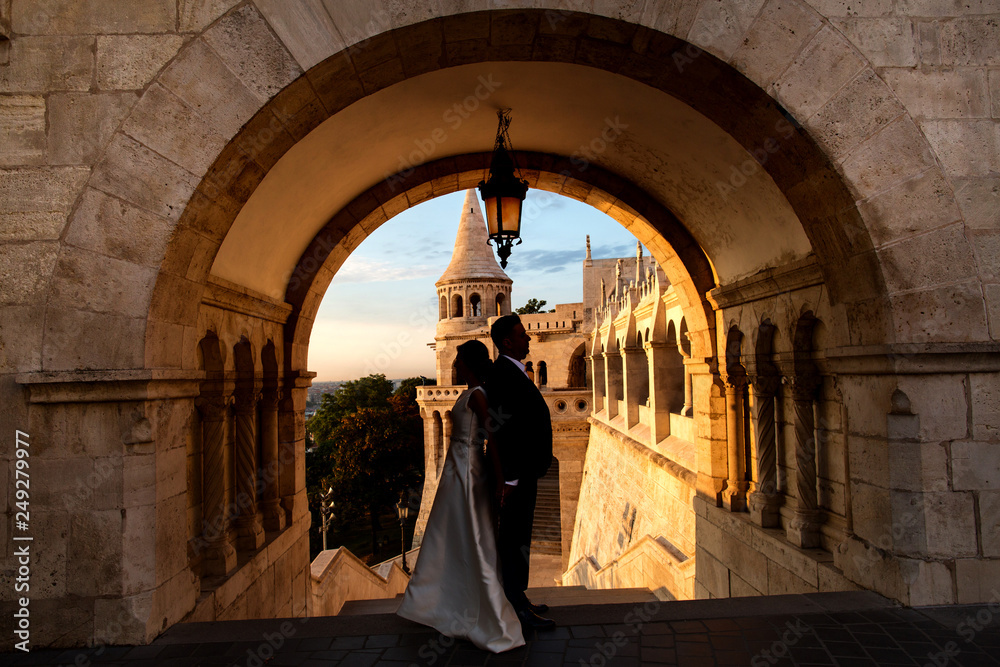 Silhouette of beautiful couple posing in old castle at sunrise