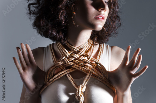 Sexy cute beautiful fashion brunette female woman adult with curve hair wears beige bodysuit and rope bandage tempting and sensual looking. Sexual erotic shibari kinbaku japanese bondage concept.