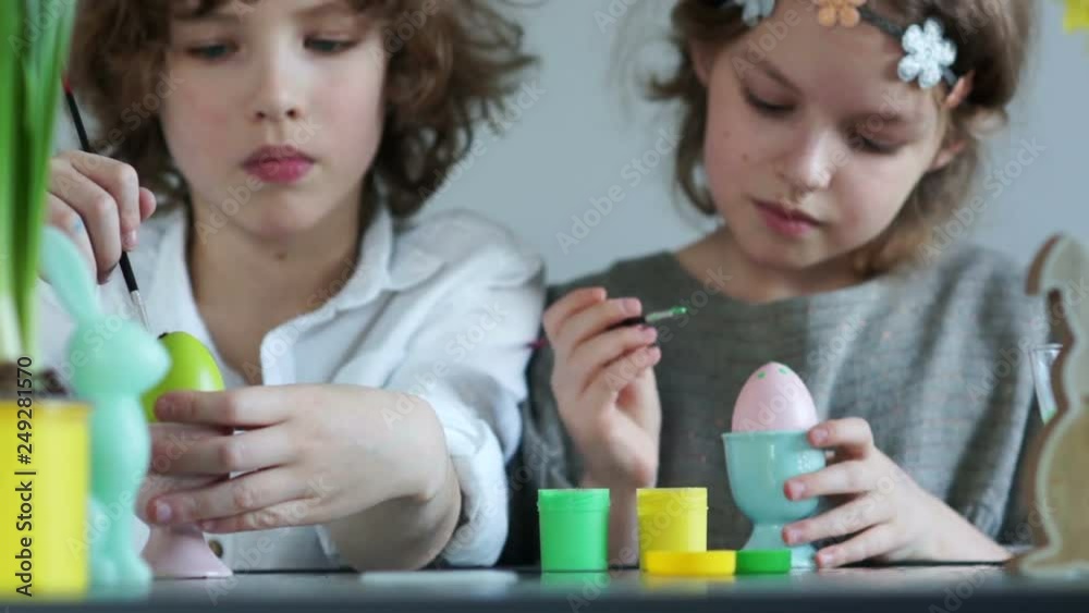 Funny schoolchildren decorate Easter eggs with tassels. Girl holding a pink egg. Happy family easter Funny schoolchildren decorate Easter eggs with tassels. Girl holding a pink egg. Happy family easter