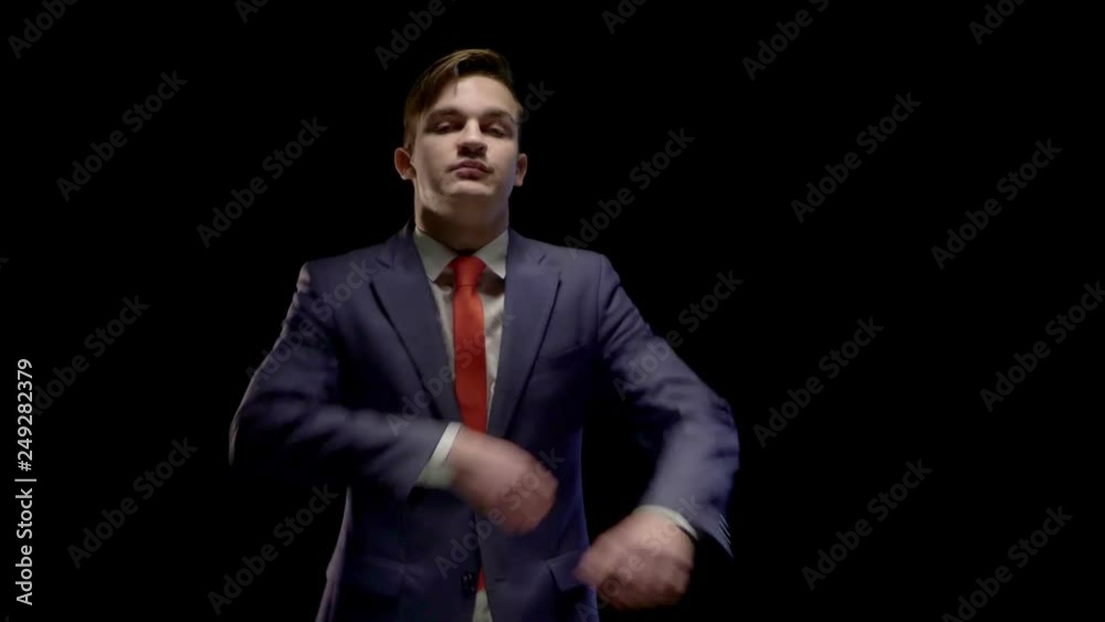 a young man of Caucasian appearance in a business suit some time in the shadows, and then exits the step and crossing his arms on his chest a young man of Caucasian appearance in a business suit some time in the shadows, and then exits the step and crossing his arms on his chest