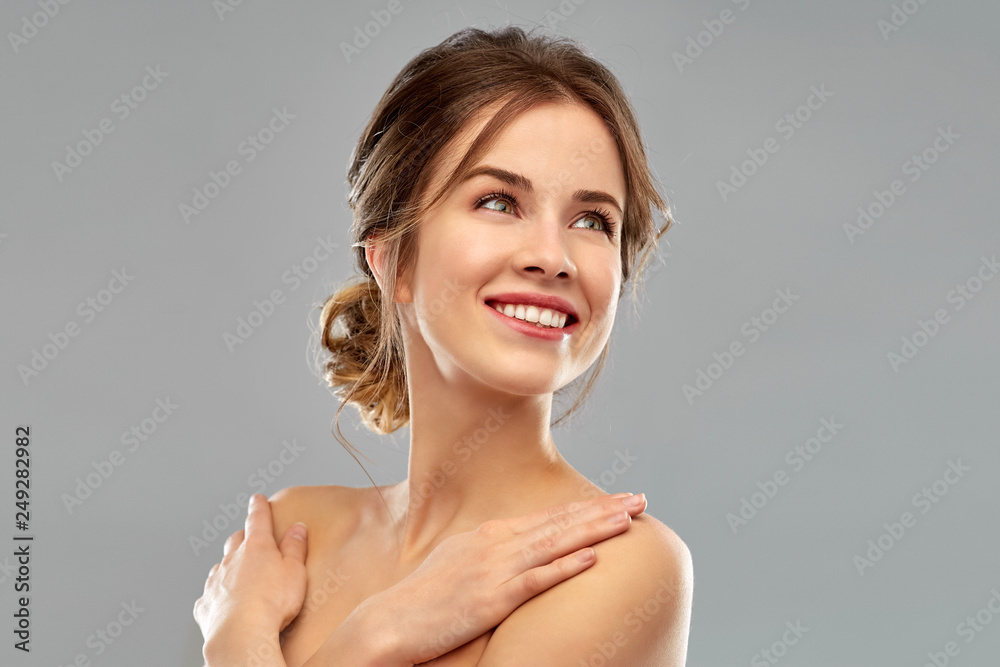 beauty and people concept - smiling young woman with bare shoulders over grey background beauty and people concept - smiling young woman with bare shoulders over grey background