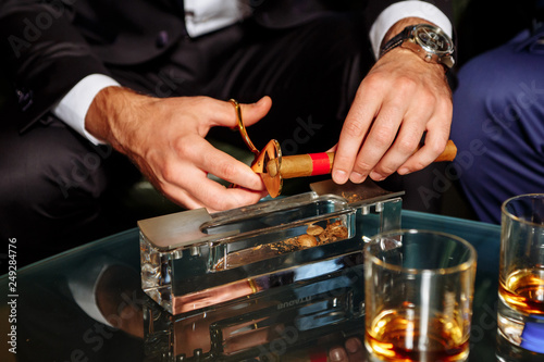 man cuts off the tip of a cigar