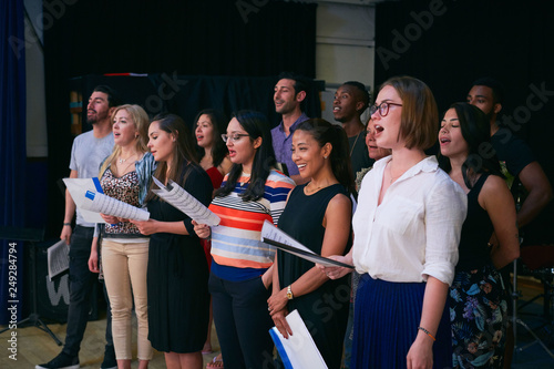 Multi-ethnic male and female students singing in choir at auditorium