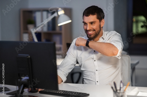 business, technology and time management concept - happy businessman using voice command recorder on smart watch at nigh office