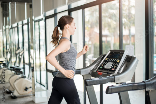 Pretty young sport woman is running on treadmill in gym, Healthy lifestyle