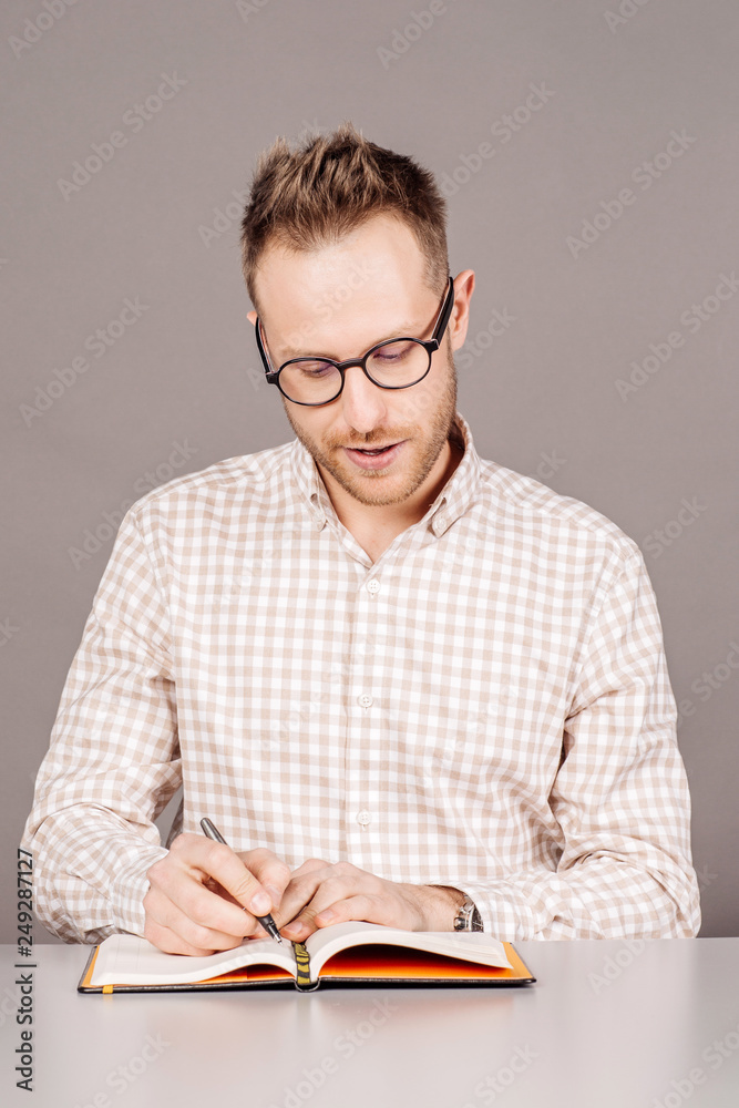 man sitting at the table with notepad over gray background. man sitting at the table with notepad over gray background.