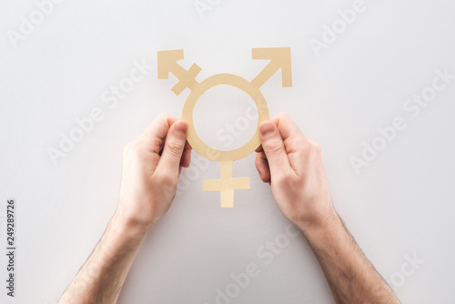 partial view of man holding white paper gender sign on grey background, lgbt concept