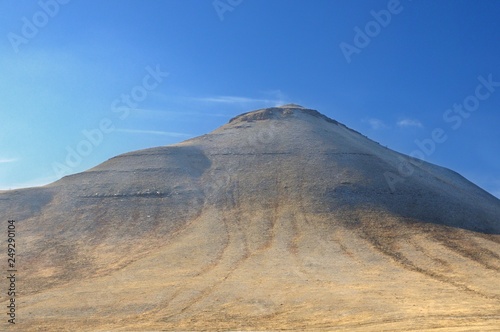 Winter landscape with a hill covered with a yellow dry grass and first snow under dark blue sky in Khakassia, Russia