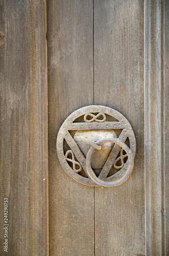 Round doorknob wih the symbol of infinity on old wooden door , Bulgaria