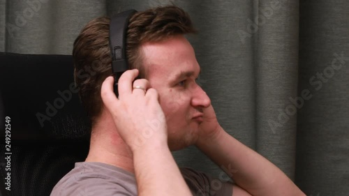 A young man sitting in a chair listening to music in headphones incredibly feeling the rhythm of music. Musical inspiration at work