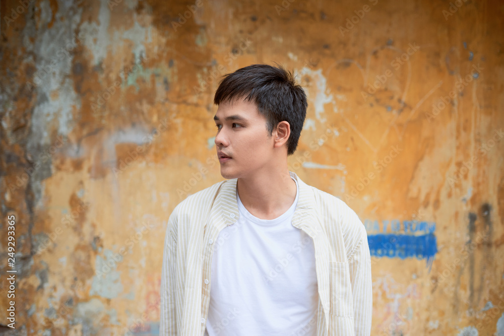 Asian man in casual clothes standing on old wall background. Asian man in casual clothes standing on old wall background.