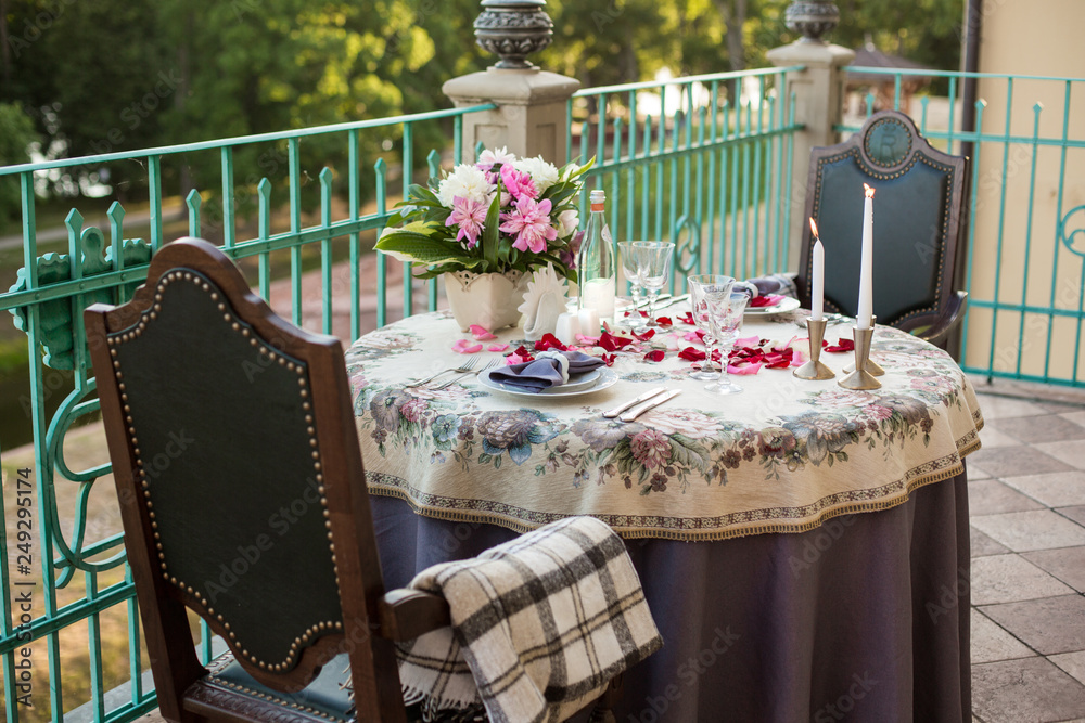 Fototapeta premium Wedding, anniversary, valentine romantic decor of the festive table in the restaurant with candles, flowers, peonies, rose petals, branches, empty wine glasses on old vintage table