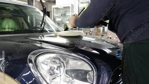 Closely shown as a professional worker polishes the transport (car) body using a polishing tool (machine). Concept from: Auto service, Car Painting, Machine washing. 