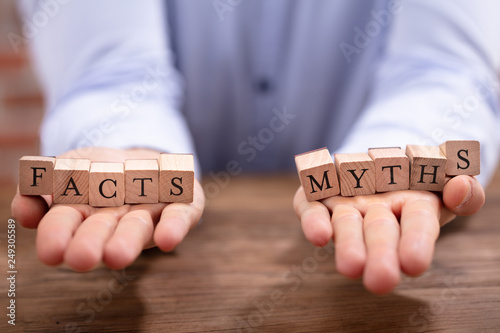Businessman Balancing Facts And Myths Blocks On His Palm photo