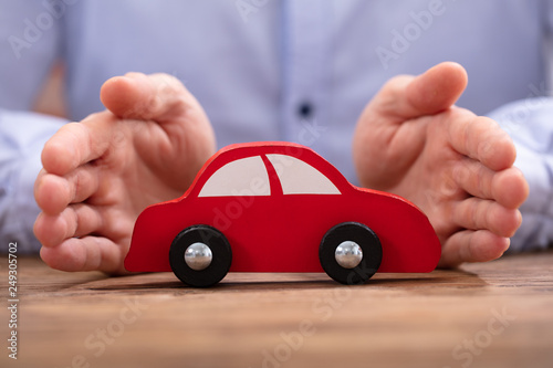 Businessman's Hand Protecting Red Toy Car