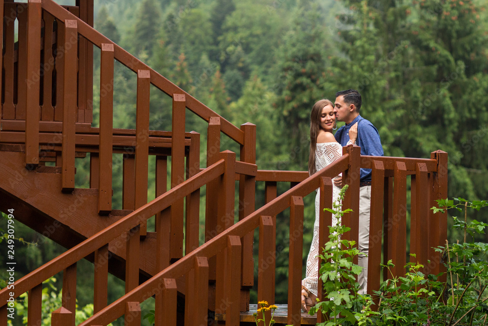 Beautiful wedding couple posing in nature at wooden structure Beautiful wedding couple posing in nature at wooden structure