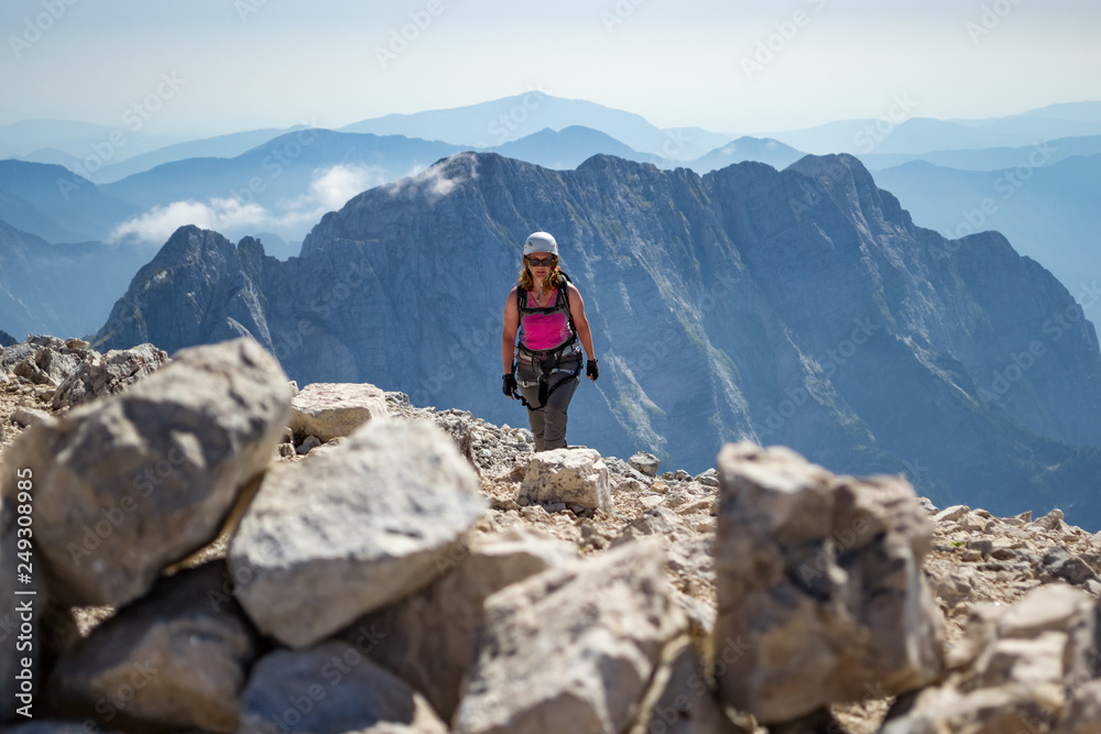 Female climber finishing a via ferrata route on Veliki Mangart (Mangrt) peak, in the Julian Alps, Triglav National Park, located at the border between Slovenia and Italy, on a bright, hot, Summer day.