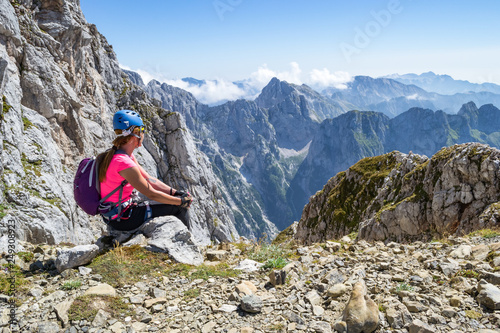 Obraz na płótnie Young girl enjoying the views from a peak in Julian Alps, Triglav National Park, Slovenia, during a break on a via ferrata route, on a hot, bright, Summer day w salonie