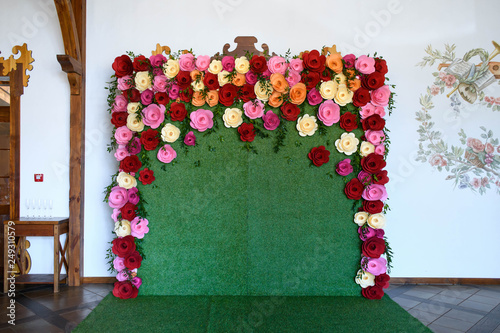 Stylish unusual wedding decoration photozone with green grasses and paper colorful flowers photo