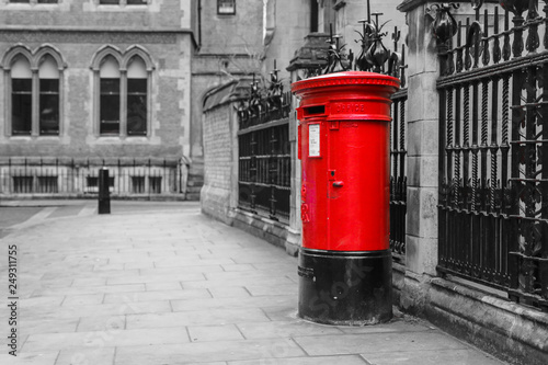 The traditional British red post box in London standing on the street. Isolated in a black and white picture. 