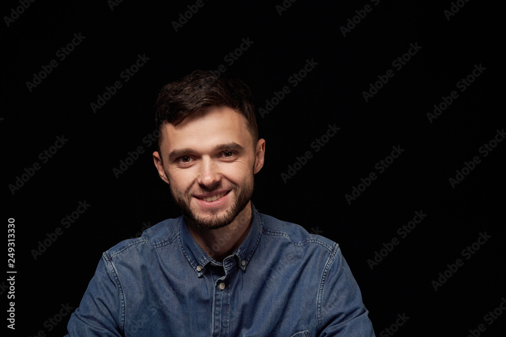 Handsome man in denim shirt looking at camera smiling