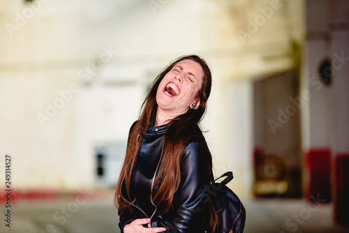 Woman surprised by a joke laughing to noisy laughter, opening her mouth widely.