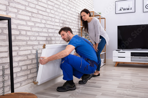 Obraz na płótnie Repairman Installing Radiator On Brick Wall At Home
