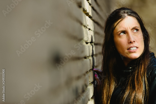 Portrait of young female model dressed in black leather posing casually in an urban setting.