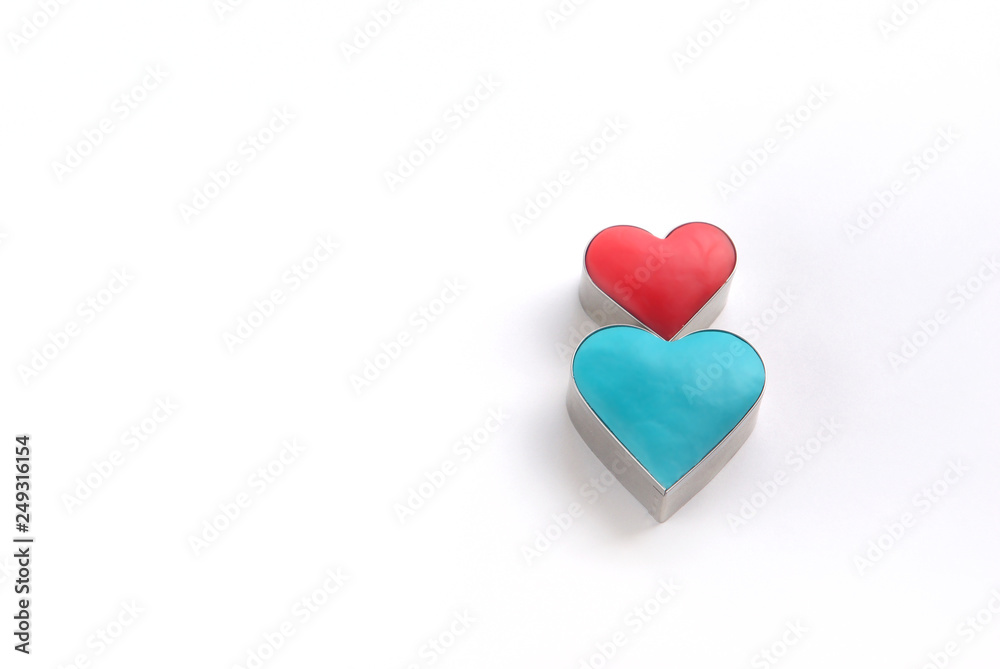 Fototapeta premium 横長の白バックに置かれた抜き型と粘土で作った赤と青のハート